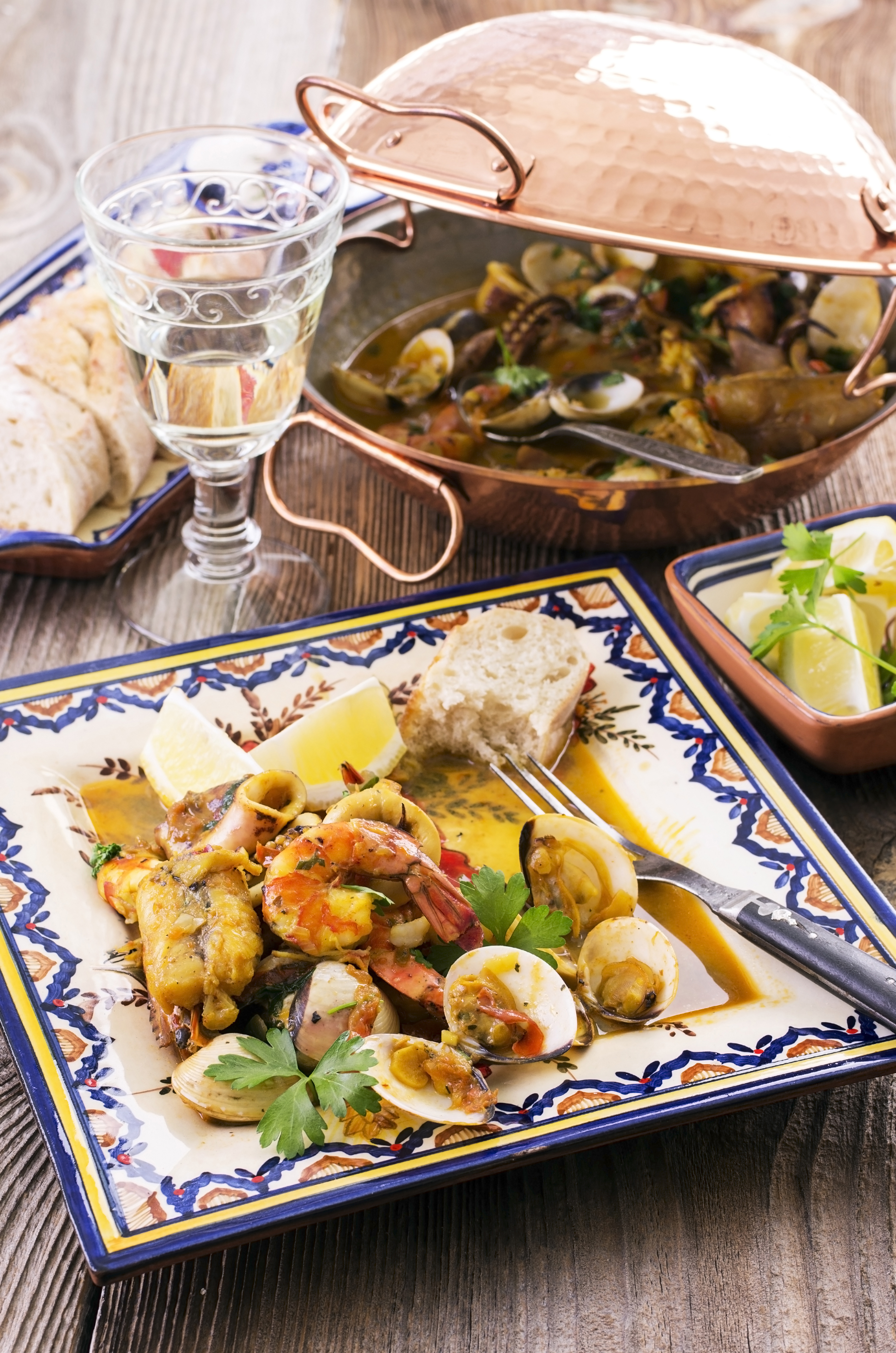 Traditionel cataplana fra Algarve regionen med friske skaldyr og fisk tilberedt i den karakteristiske kobbergryde, serveret rustikt på træbord