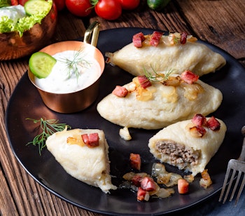 Traditionelle cepelinai - Litauens nationalret med kartoffelboller fyldt med kød og toppes med sprød bacon, serveres i restauranter i Vilnius