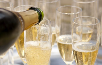 Gylden champagne der hældes i elegante glas med funklende bobler, perfekt til luksuriøse fejringer og festlige skåle på rejsen