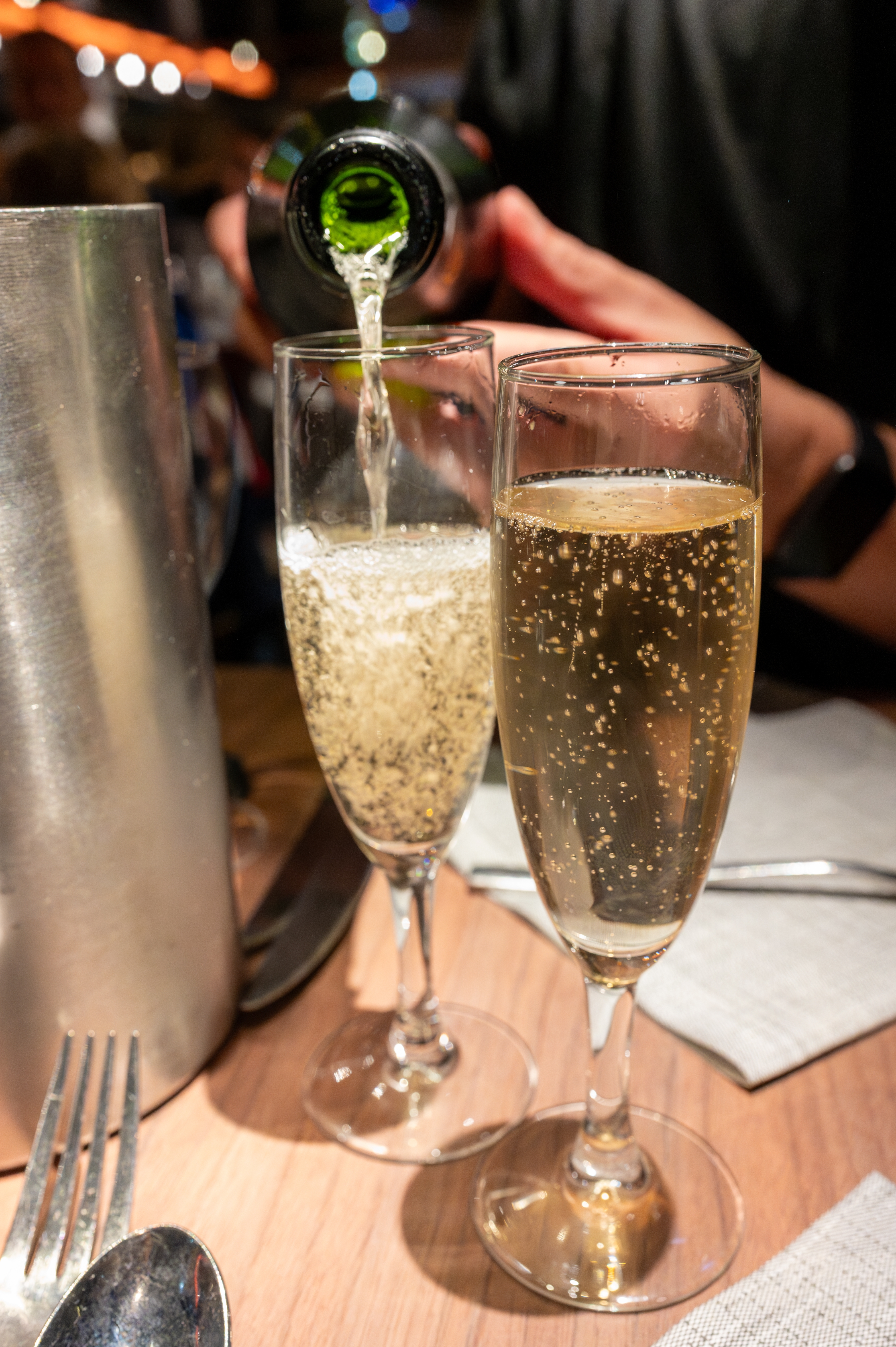 To champagneglas bliver fyldt op under en romantisk middagskrydstogt på Seinen i Paris, Frankrig