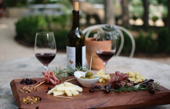 Lækker charcuterie anretning med oste, pølser og rødvin på en udendørs terrasse i Napa Valley vingård