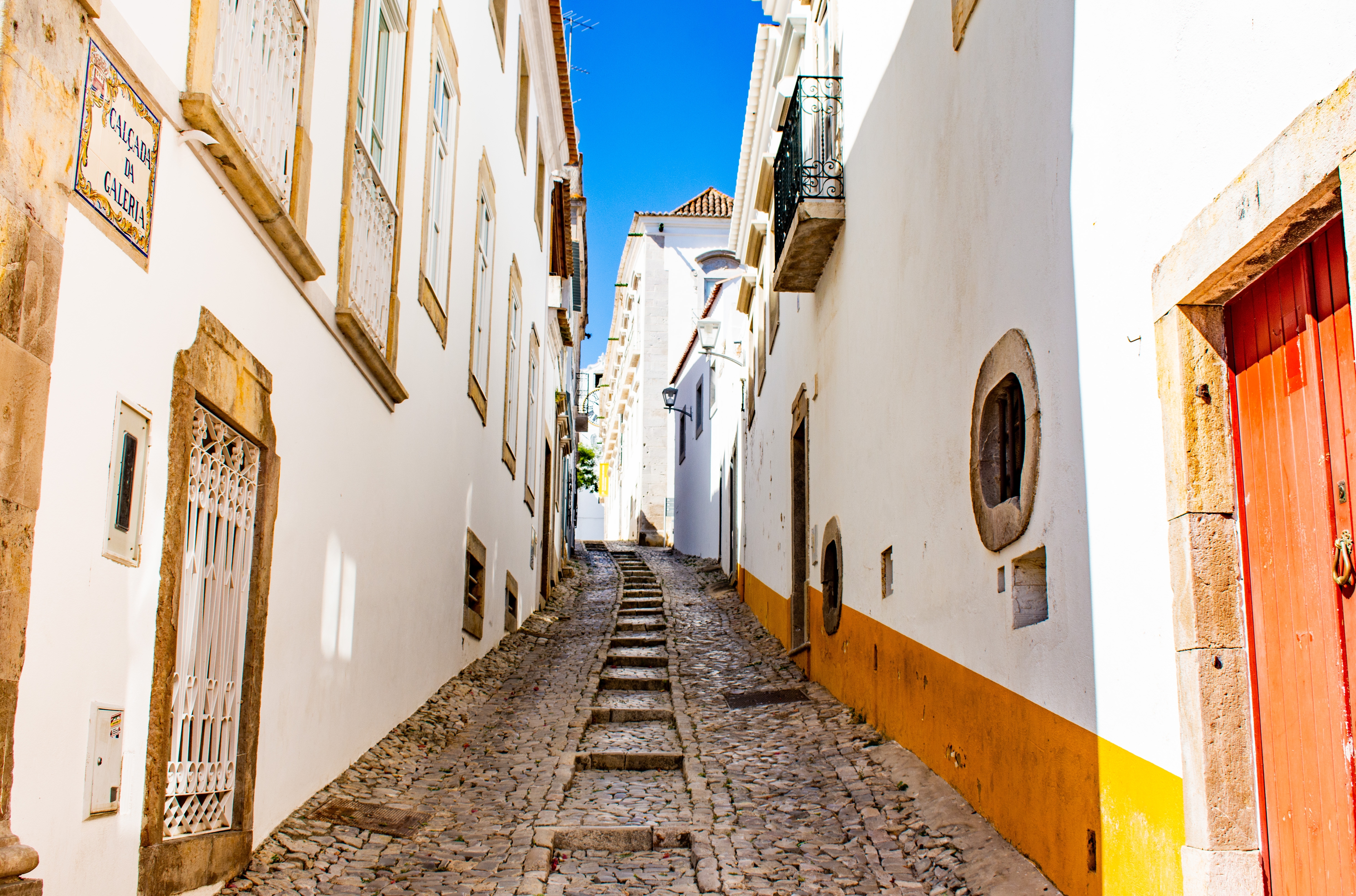 Idyllisk brostensgade med hvidkalkede bygninger i det historiske centrum af Tavira i Algarve, Portugal