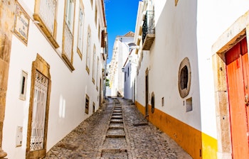 Idyllisk brostensgade med hvidkalkede bygninger i det historiske centrum af Tavira i Algarve, Portugal