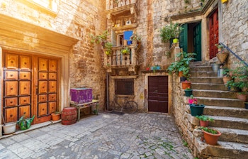 Idyllisk smal gade med historiske stenbygninger i den UNESCO-beskyttede middelalderby Trogir i Kroatien