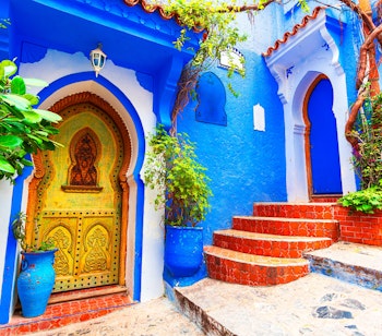 Karakteristiske blå trapper og vægge med farverige blomsterkrukker i Chefchaouens gamle medina, Marokkos berømte blå by i Nordafrika