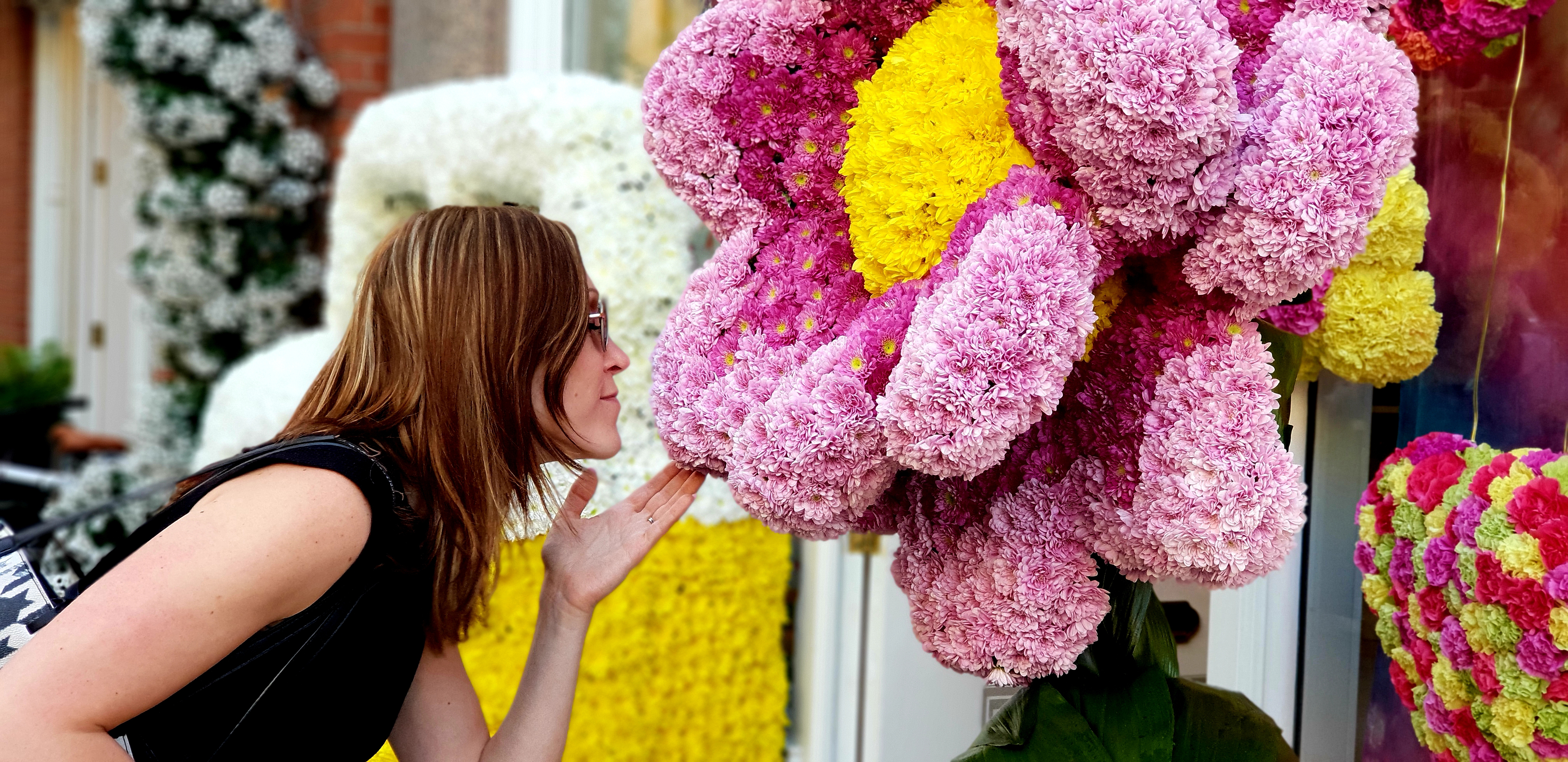 Ung kvinde foran farverig blomsterudstilling ved Chelsea Flower Show i London, en populær havebegivenhed i foråret