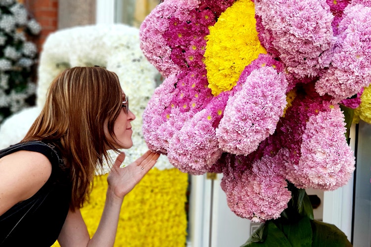 Ung kvinde foran farverig blomsterudstilling ved Chelsea Flower Show i London, en populær havebegivenhed i foråret