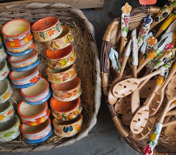 Farverige keramikskåle og træskeer i kurve til salg som lokale souvenirs i Riomaggiore, Cinque Terre på den italienske riviera