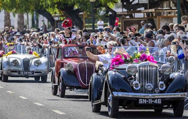 En stribe af gamle veteranbiler kører ned af gaden til bifald fra et jublende publikum