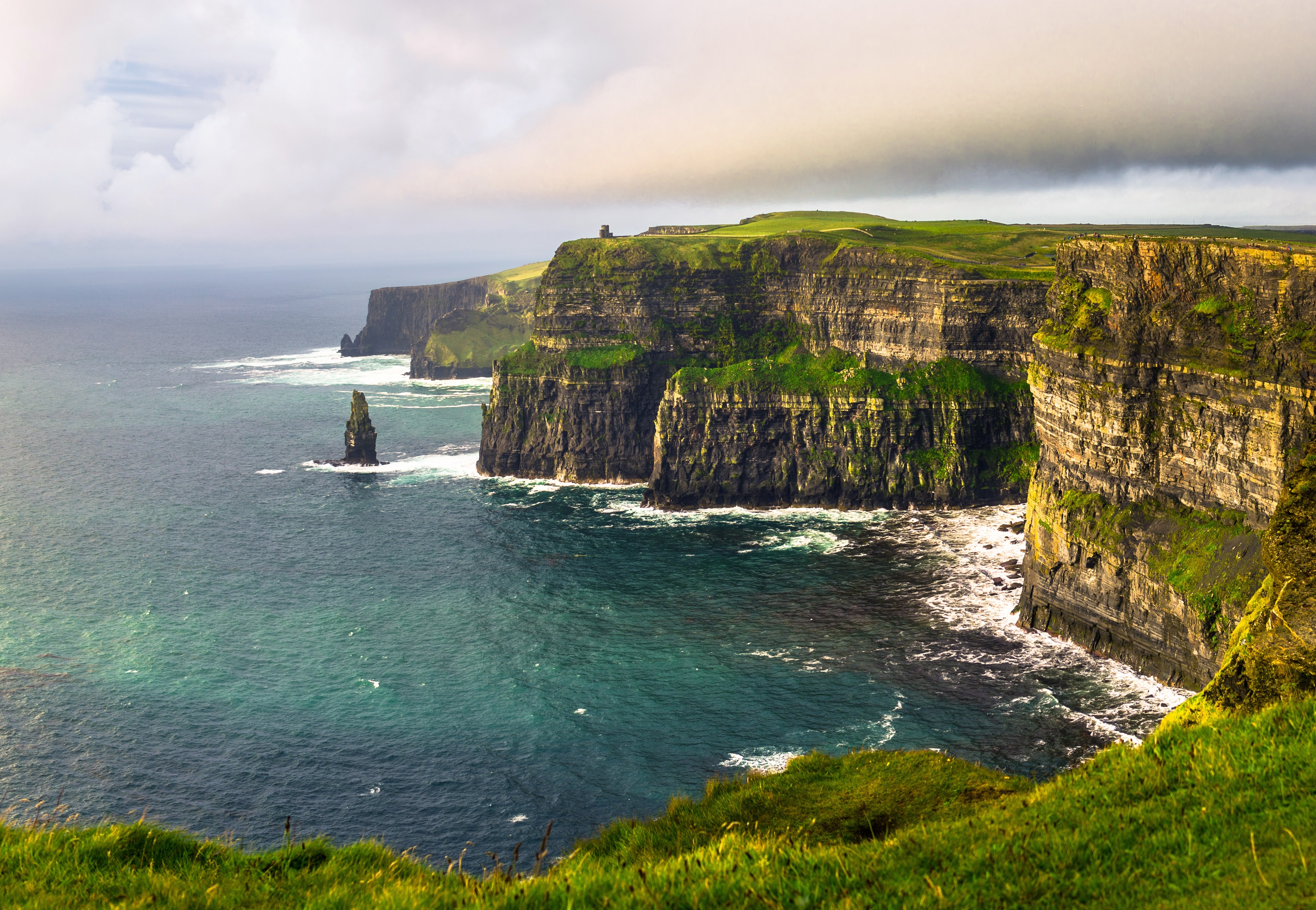 Cliffs of Moher Irland - dramatiske grønne klipper ved Atlanterhavet med bølger og blå himmel