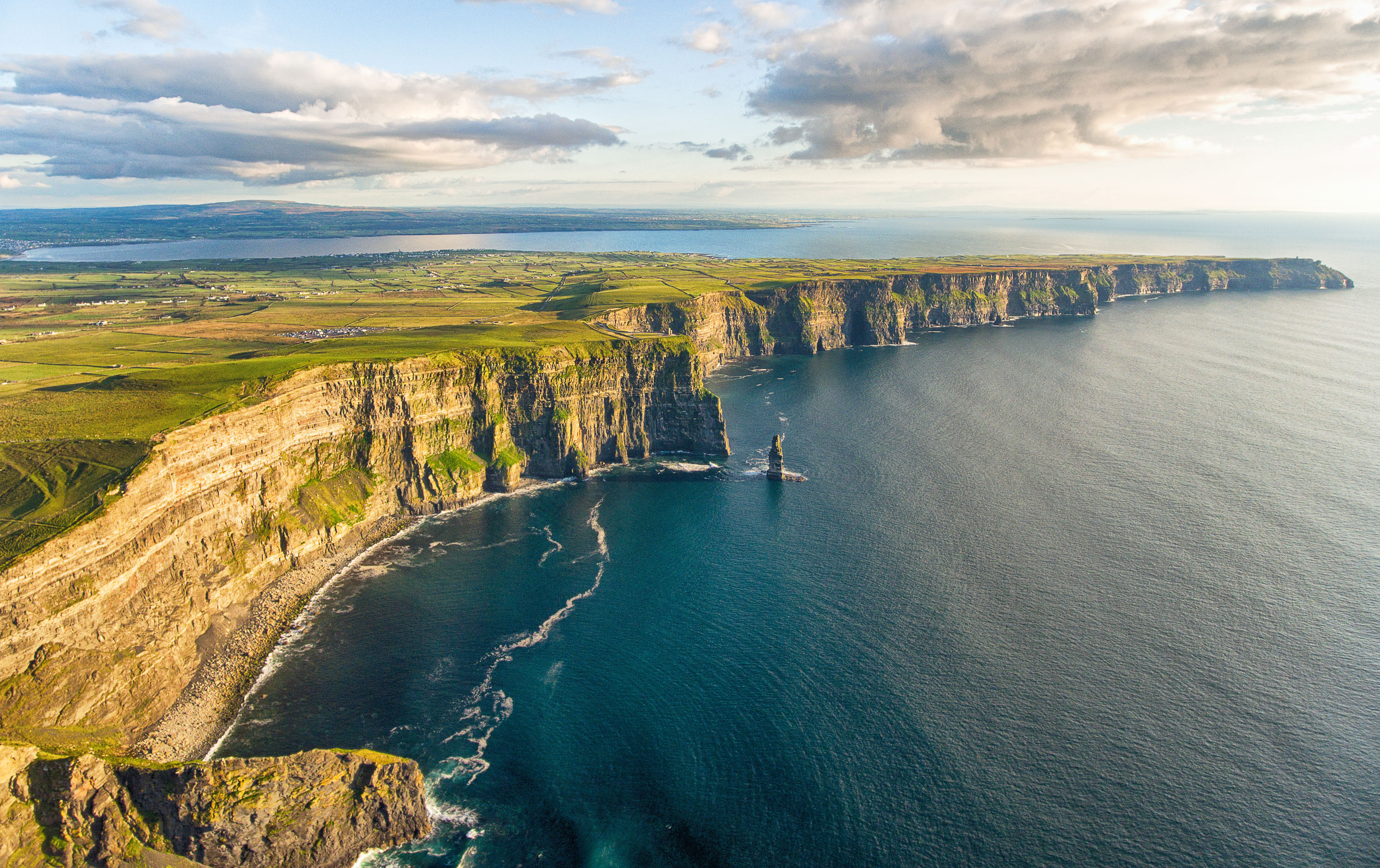 Cliffs of Moher i Irland - dramatiske kysteklipper med grønne marker og blåt hav