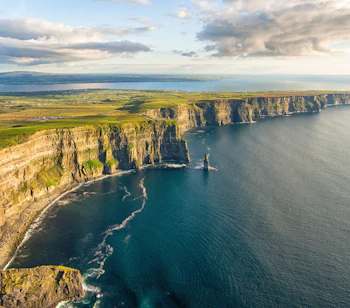 Cliffs of Moher i Irland - dramatiske kysteklipper med grønne marker og blåt hav