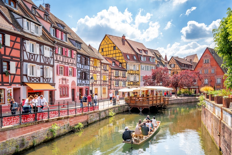Malerisk udsigt over Lille Venedig i Colmar med farverige bindingsværkshuse langs kanalen, turistbåd på vandet og charmerende stemning i hjertet af Alsace