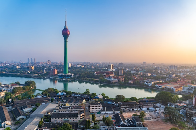 Luftfoto af Colombo bysilhuet ved solnedgang med Lotus Tower og sørefleksion i Sri Lanka