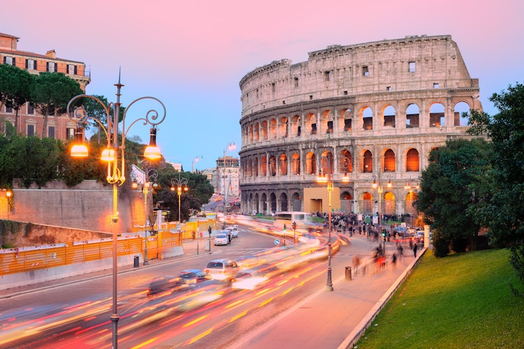 Det historiske Colosseum badet i solnedgangens gyldne lys med trafikspor fra byens pulserende gader i forgrunden, Rom, Italien