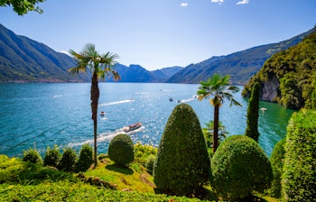 Malerisk udsigt over Comosøen i Norditalien med farverige huse, azurblåt vand og dramatiske bjerge på en solrig sommerdag
