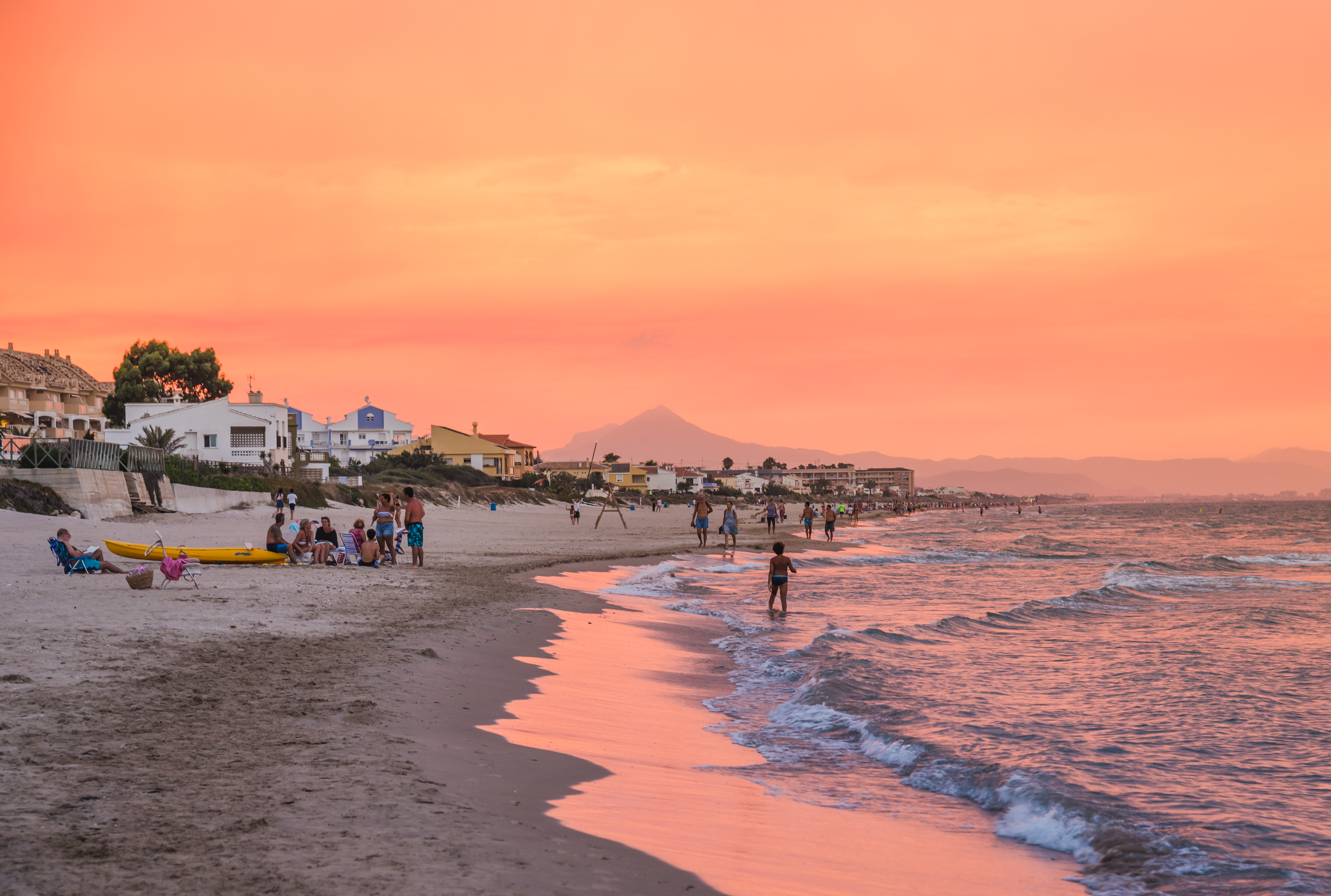 Smuk solnedgang over Costa Blanca strand i Spanien med turister der nyder den gyldne time ved Middelhavet