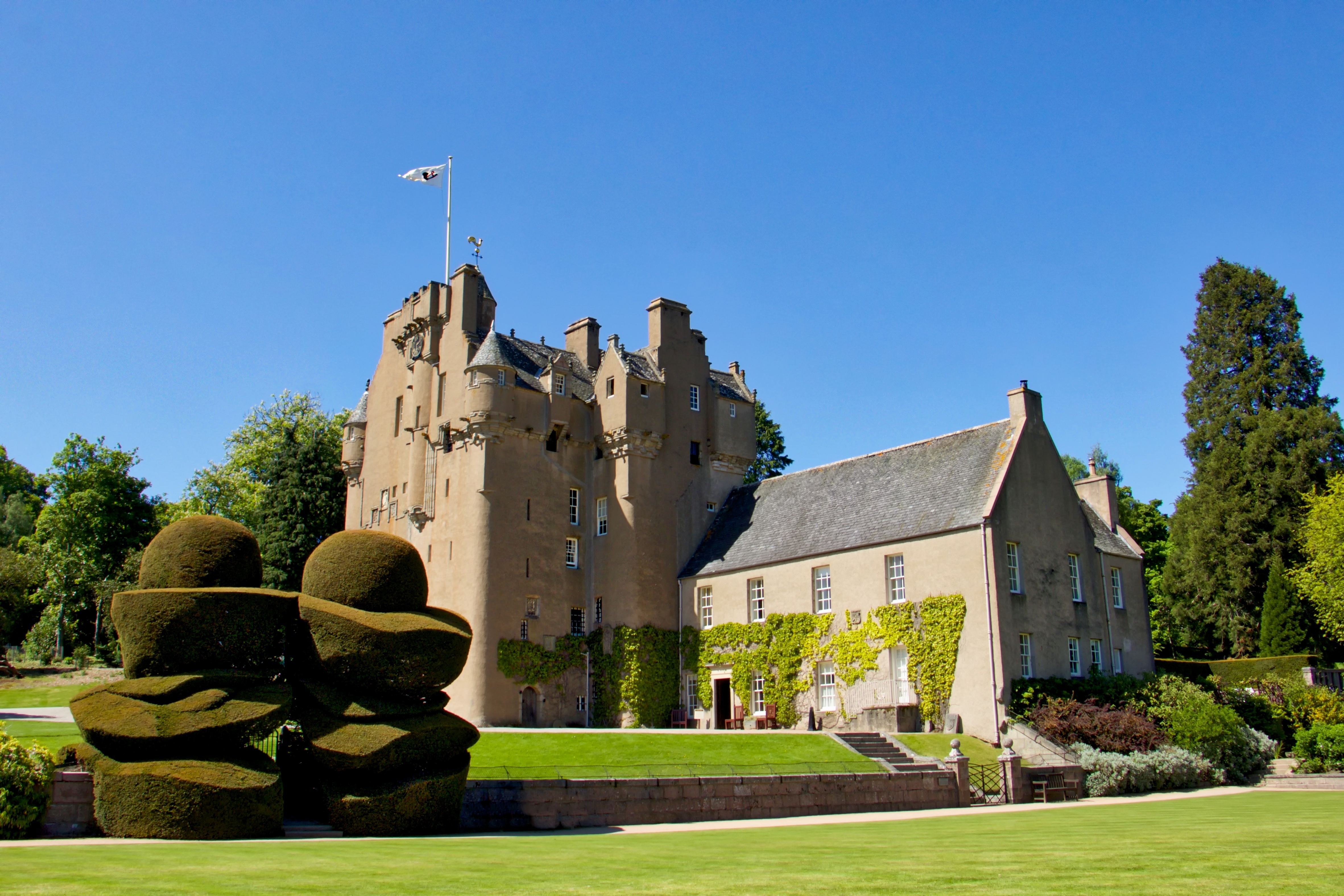 Crathes Castle i Aberdeenshire, Skotland, med smukke topiarhaver og flag i strålende solskin