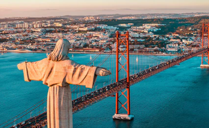 Cristo Rei statue med udsigt over Lissabons 25. april bro og Tejo floden ved solnedgang