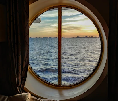 Luksus cruiseskib kahyt med rundt vindue og smuk solnedgang over havet