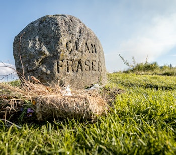Historisk mindesten på Culloden slagmarken i Skotland omgivet af det grønne højlandslandskab, der markerer stedet for det afgørende slag i 1746