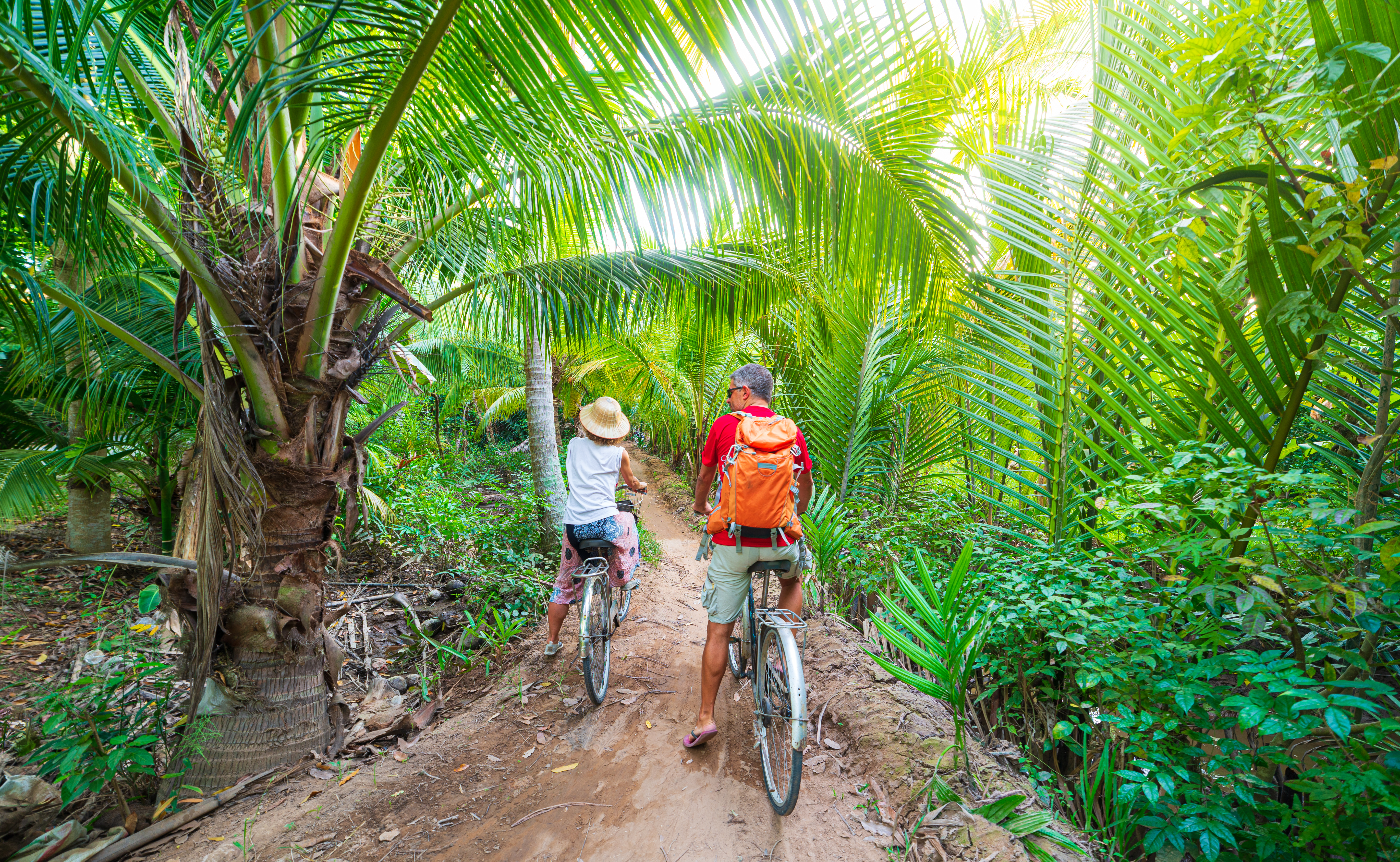 Par på cykeltur gennem tropisk palleskov i Mekong Delta, Ben Tre, Vietnam