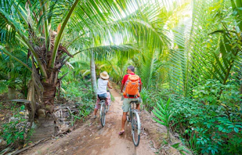 Par på cykeltur gennem tropisk palleskov i Mekong Delta, Ben Tre, Vietnam