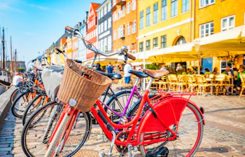 Farverige cykler parkeret langs Nyhavn kanal med traditionelle danske bygninger i København