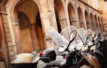 Nærbillede af cykler parkeret på række foran en historisk bygning i Bologna, Italien - perfekt til en autentisk italiensk byoplevelse