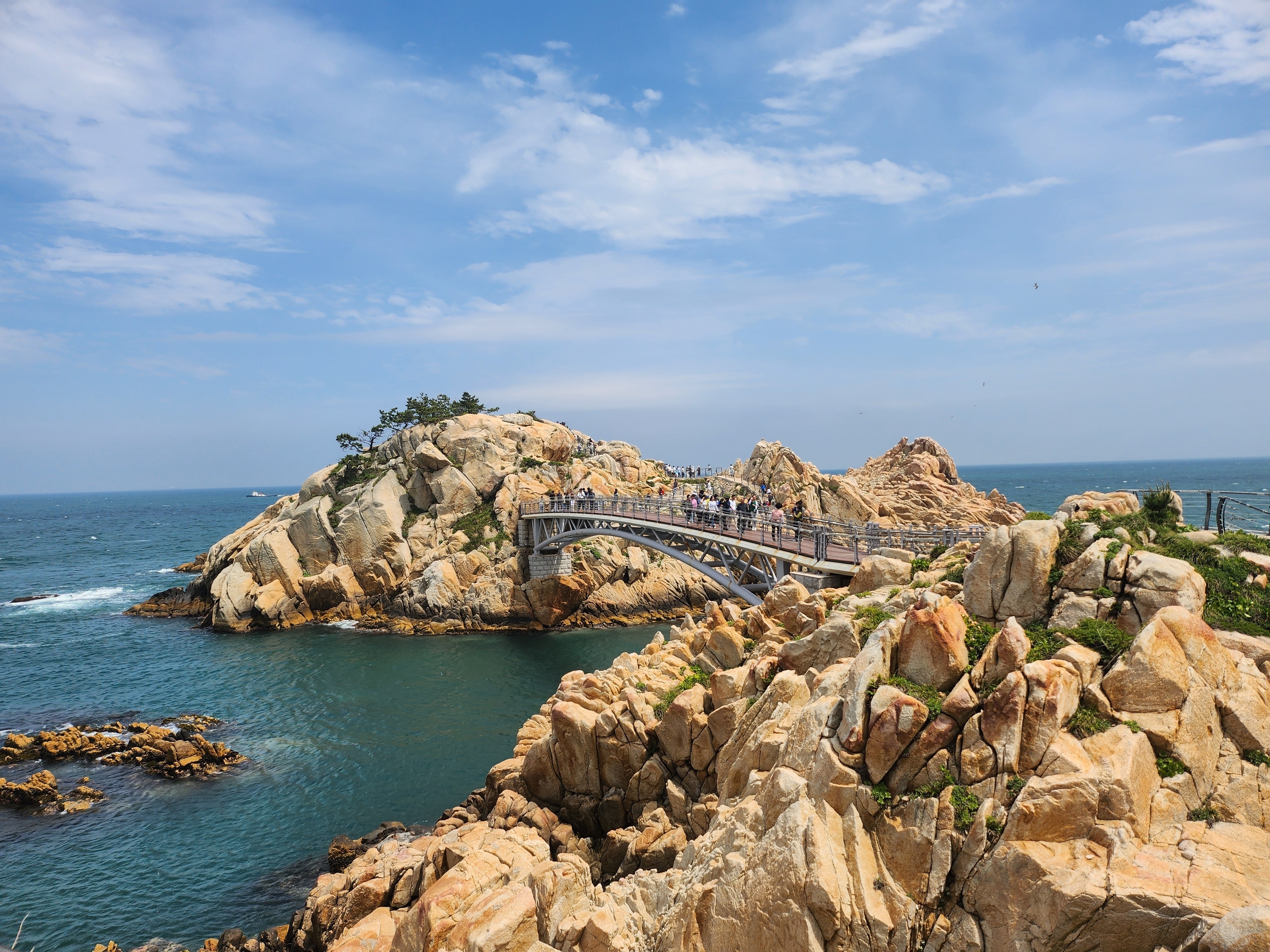 Imponerende klippeformationer der ligner dinosaurfossiler i Daewangam Park, Ulsan, med en bro over det blå havvand i Sydkorea