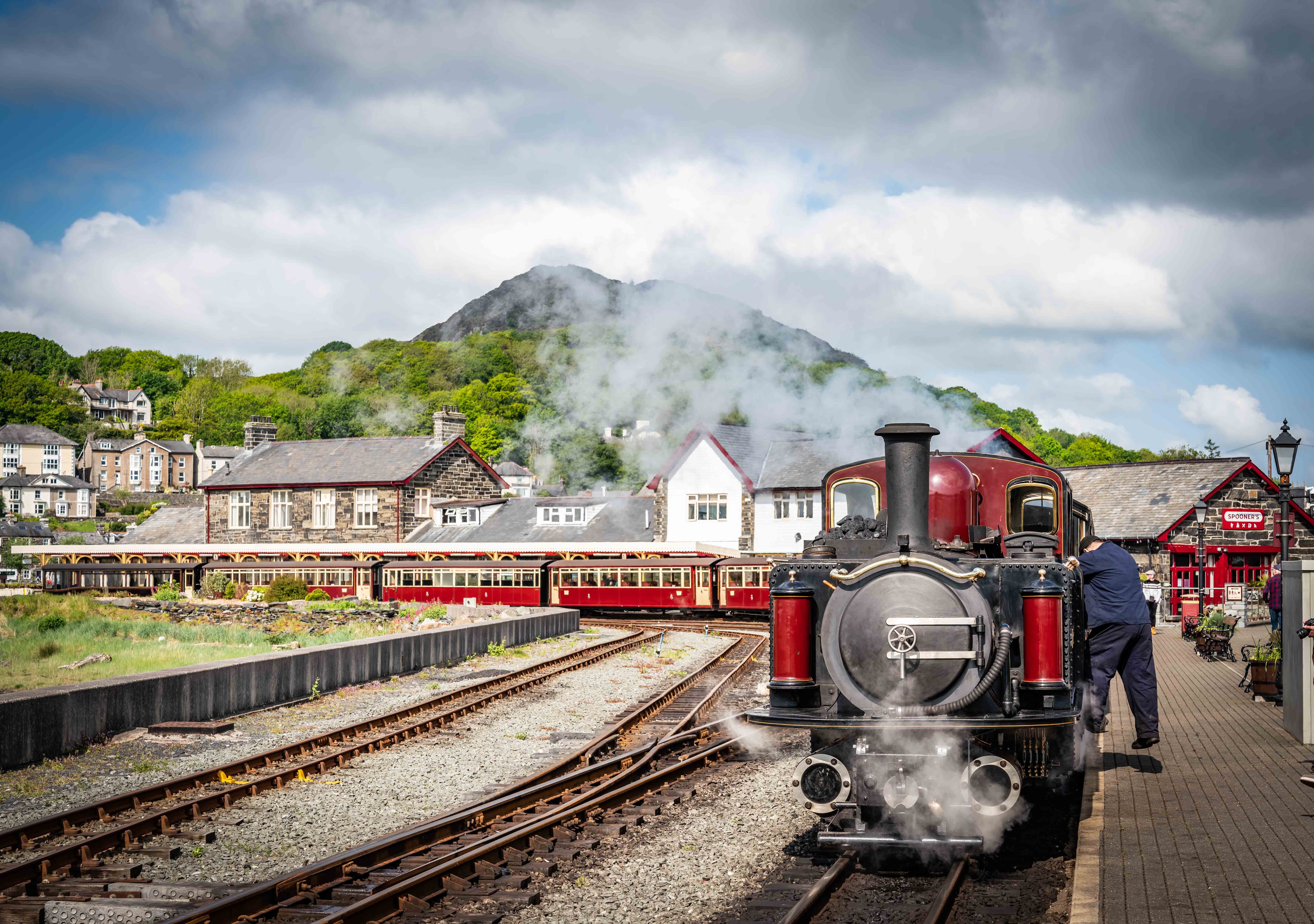 Historisk damptog på Porthmadog station med Snowdonia bjerge i baggrunden, Wales