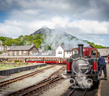 Historisk damptog på Porthmadog station med Snowdonia bjerge i baggrunden, Wales