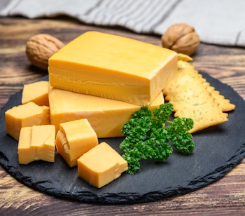 Traditionel dansk osteplatte med gul ost, kiks og persille på skiferplade