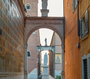 Dante Alighieri statue på Piazza Signori i Veronas historiske centrum med buegang og middelalderlig arkitektur i Veneto-regionen