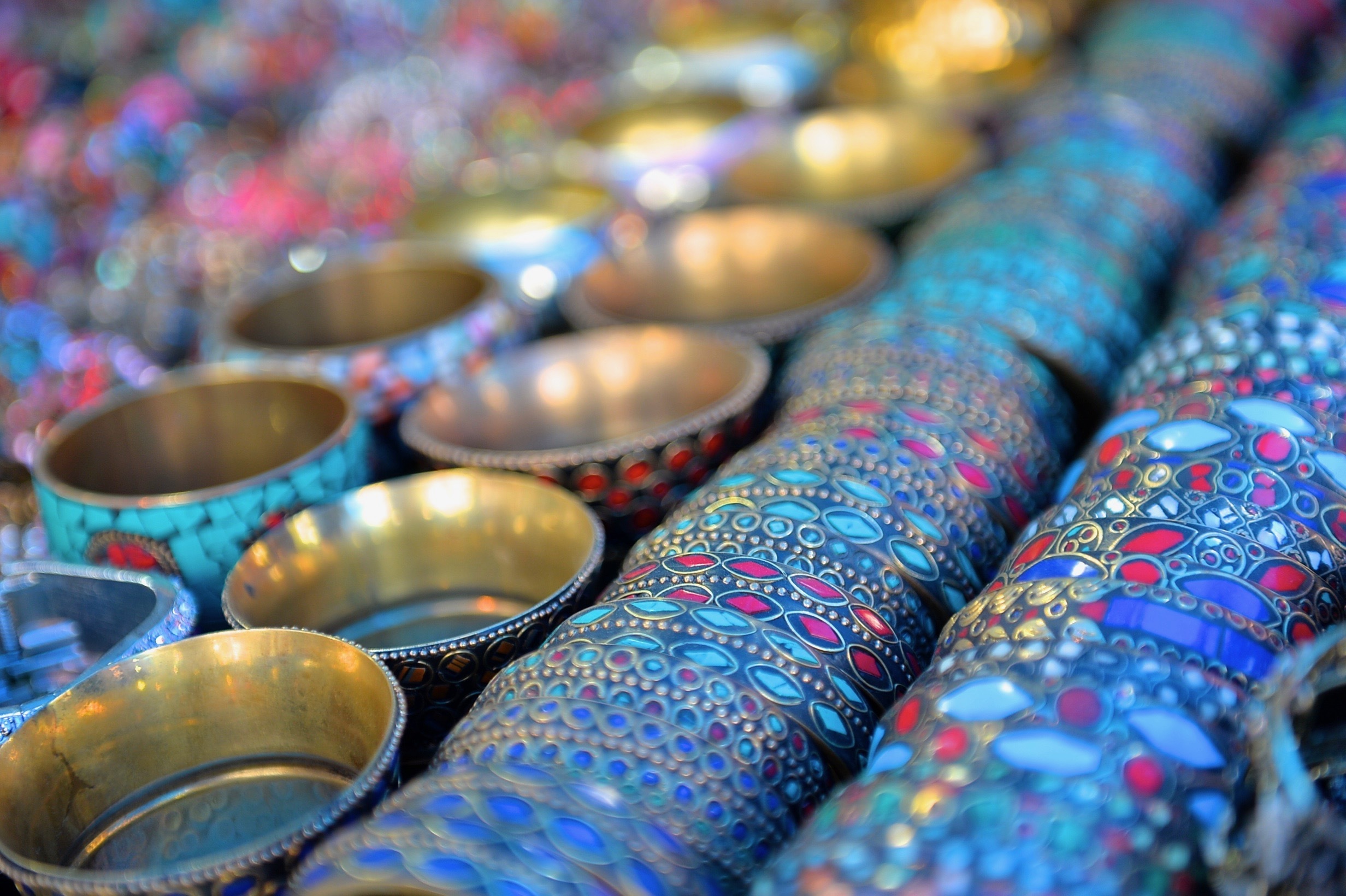 Rækker af smukt dekorerede metalliske håndværkskopper med livlige blå og gyldne mønstre udstillet på et traditionelt marked i Delhi, Indien