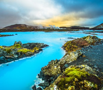 Turister nyder det varme mineralrige vand i Den Blå Lagune, et berømt geotermisk spa på Reykjanes-halvøen i Island