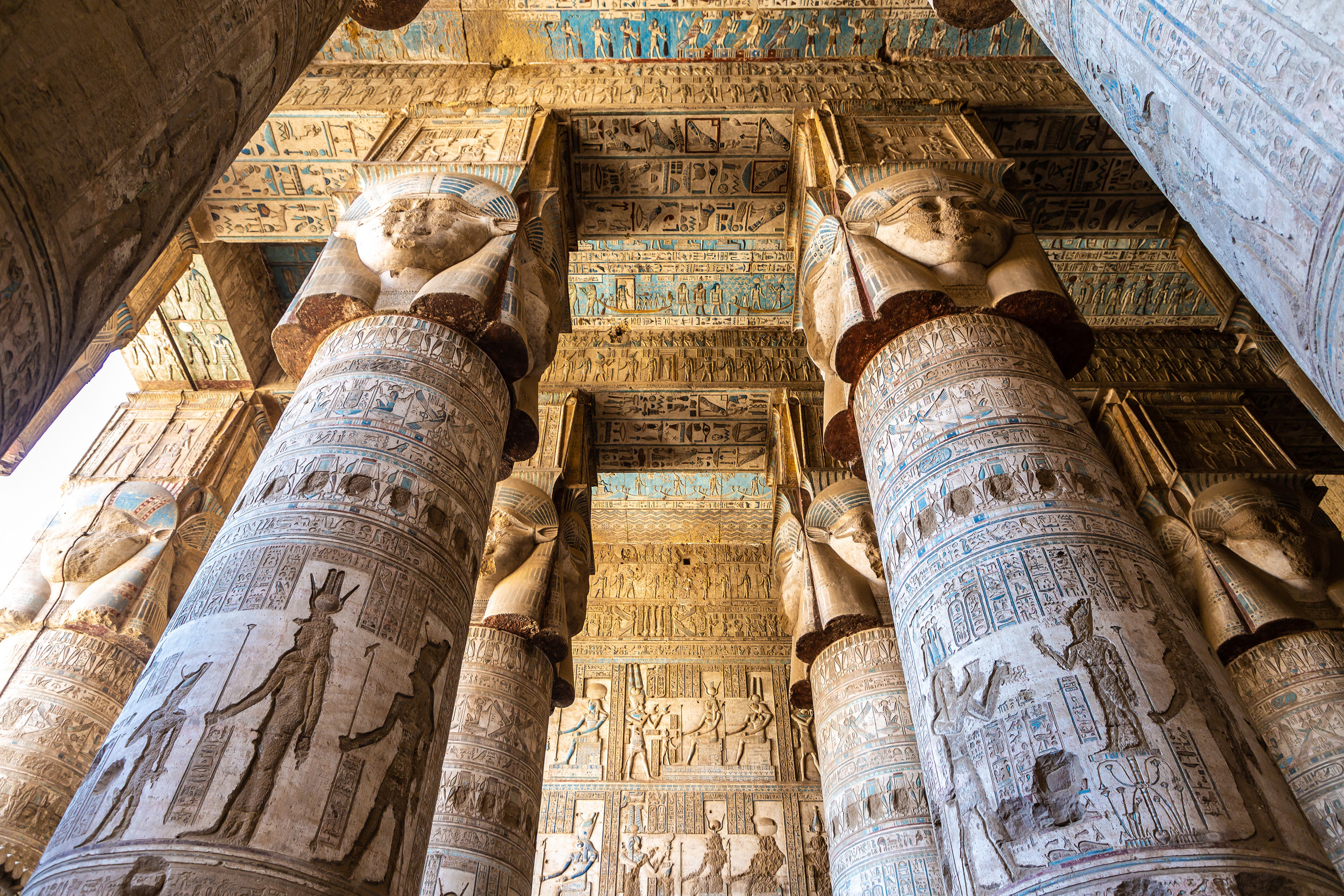 Pragtfulde udskårne søjler med Hathor-ansigter og farverige hieroglyffer i Dendera-templet nær Luxor i Egypten