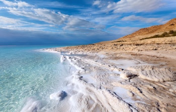 Fredfyldt kystlinje ved Det Døde Hav i Jordan med turkisblåt vand og klar himmel i solskin