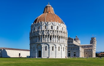 Det berømte skæve tårn i Pisa og den imponerende katedral med hvid marmorfacade på Piazza dei Miracoli under blå himmel i Toscana, Italien
