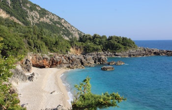 Betagende Dhermi strand med krystalklart turkisblåt vand og hvidt sand omgivet af klipper i Himara, Albanien