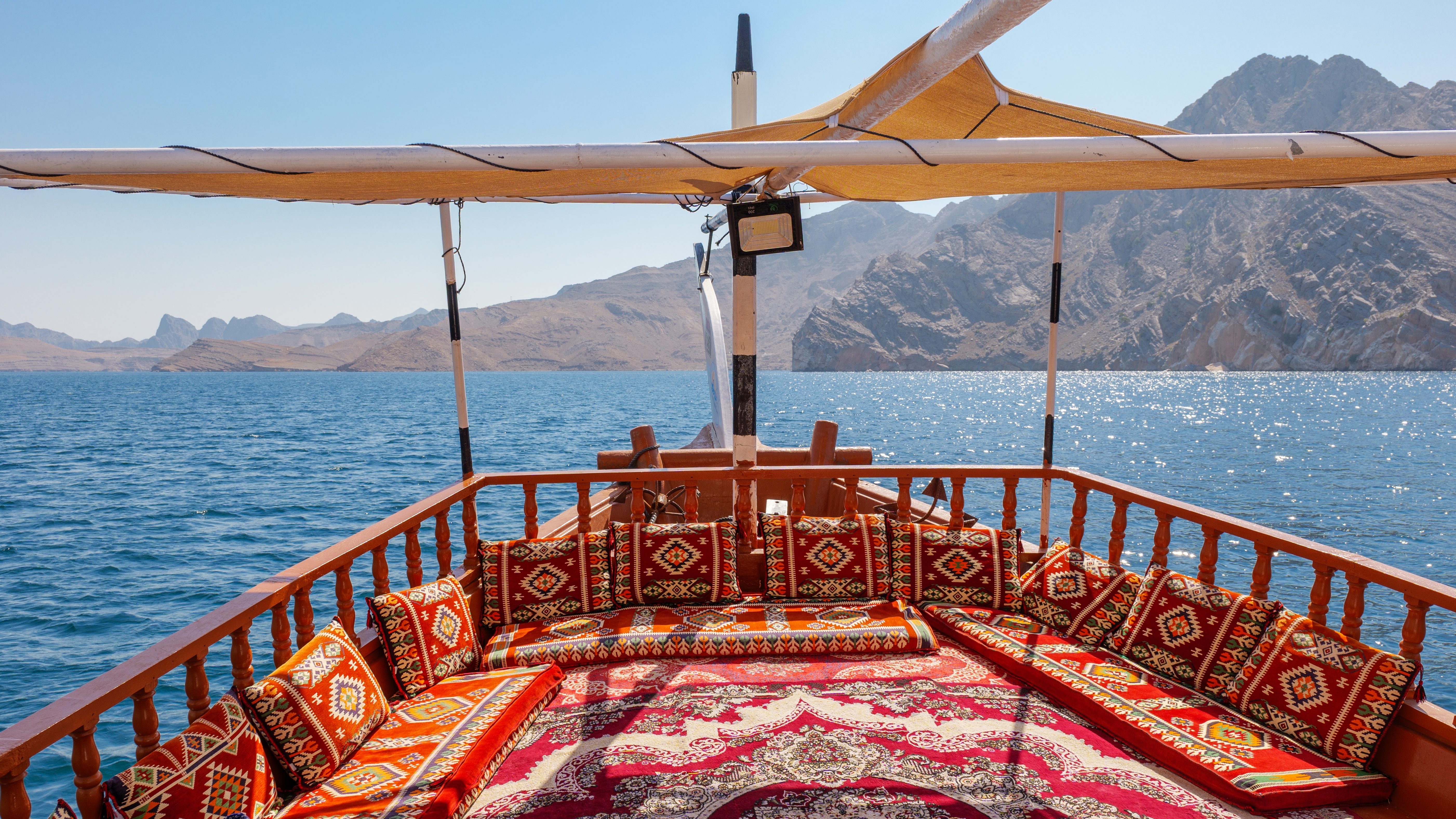 Traditionel dhow båd cruise i Musandam fjordene Oman med røde puder og bjerglandskab