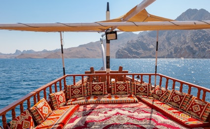 Traditionel dhow båd cruise i Musandam fjordene Oman med røde puder og bjerglandskab