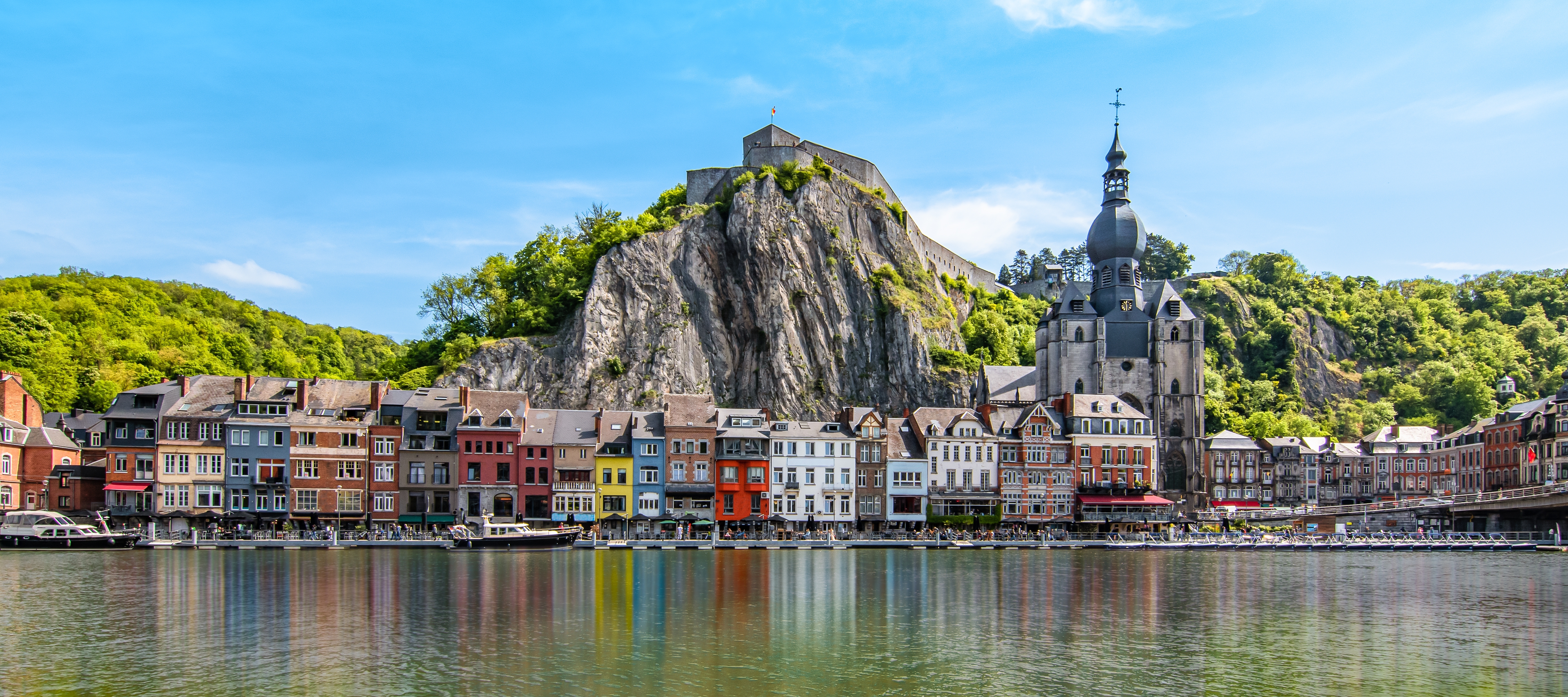 Smukt panorama af Dinant i Belgien med farverige huse langs Meuse-floden og historisk citadel
