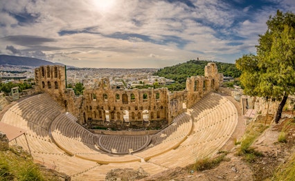 Det antikke Dionysus-teater i forgrunden med den berømte Akropolis-høj og Parthenon-templet i baggrunden, to ikoniske seværdigheder i Athens historiske centrum