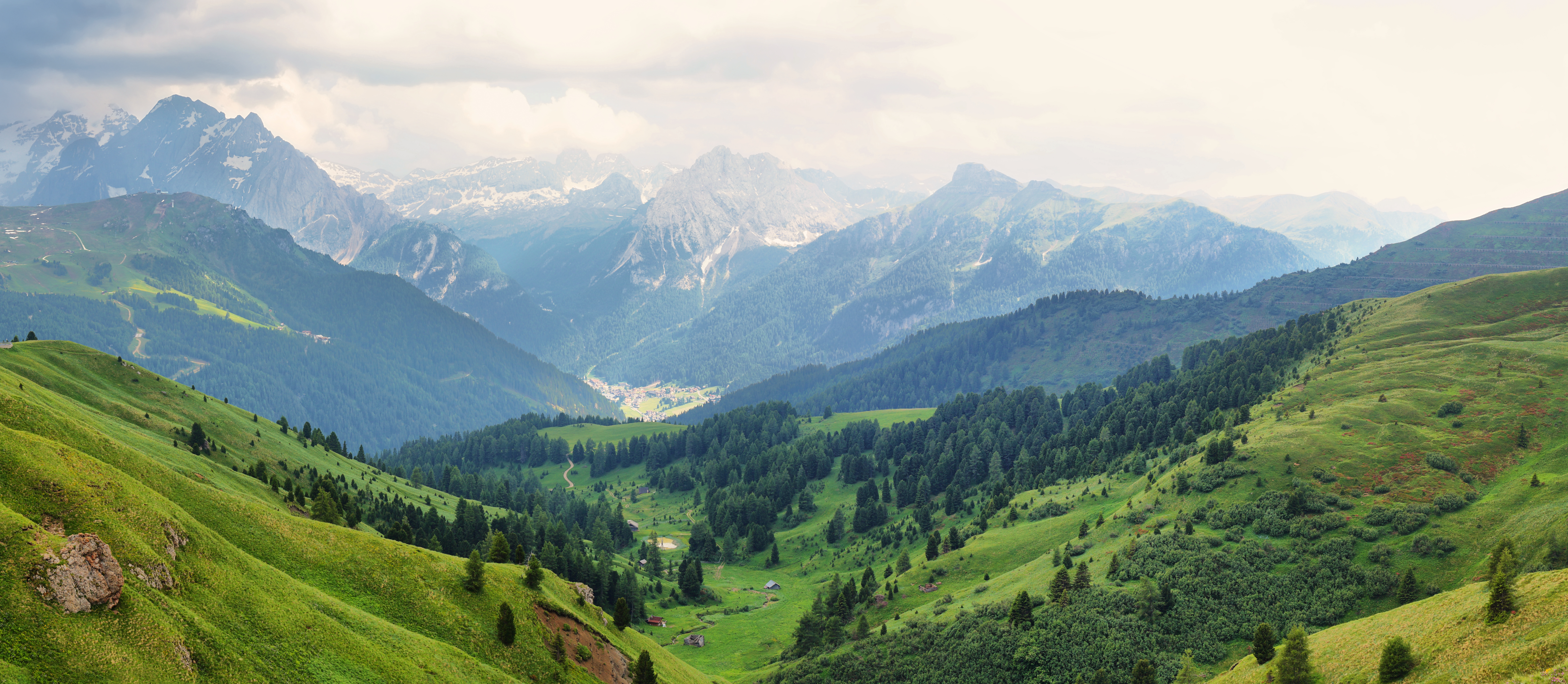 Panoramaudsigt over den grønne Dolomit-dal med landsbyen Canazei og dramatiske bjergtoppe set fra Sella-passet i Sydtyrol, Italien