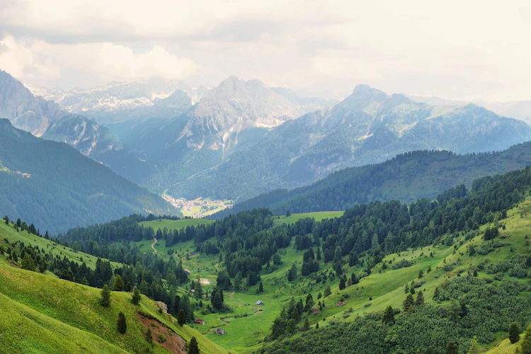 Panoramaudsigt over den grønne Dolomit-dal med landsbyen Canazei og dramatiske bjergtoppe set fra Sella-passet i Sydtyrol, Italien