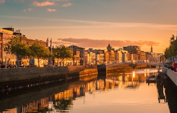 Betagende solnedgangsudsigt over Dublins bycentrum med floden Liffey, der reflekterer de farverige bygninger i den gyldne aftenbelysning