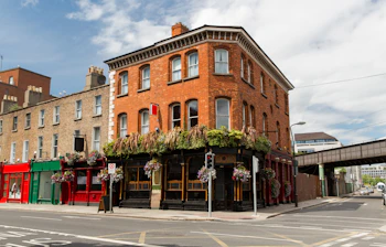 Traditionel irsk pub med røde mursten og blomsterkurve på gadehjørne i Dublin, Irland