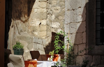 Charmerende gadecafé med borde og stole mellem historiske stenmure i Dubrovniks gamle bydel, Kroatien - en idyllisk feriedestination ved Adriaterhavet