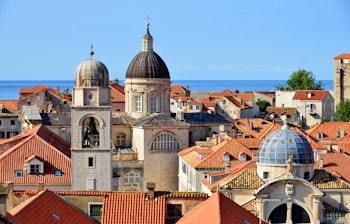 Panoramaudsigt over Dubrovniks historiske gamle bydel med røde tegltage og den azurblå Adriaterhavskyst i Kroatien